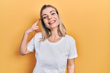 Fototapeta premium Beautiful caucasian woman wearing casual white t shirt smiling doing phone gesture with hand and fingers like talking on the telephone. communicating concepts.