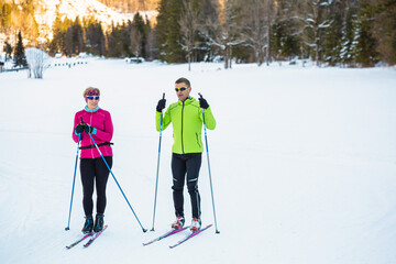 Middle aged couple, cross country skiers, standing on a ski trail and looking at incredible snow...