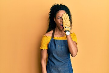 Middle age african american woman wearing professional apron yawning tired covering half face, eye and mouth with hand. face hurts in pain.