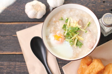 Joke or Congee in a Thai style cup Served on a black wooden table. It's an Asian breakfast. on top view