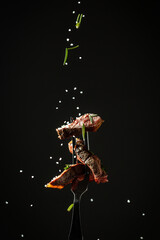 Grilled beef steak with spices on a black background. Beef steak on a fork sprinkled with rosemary...