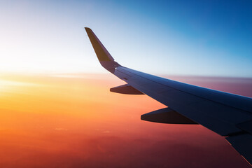 View from the window of the aircraft on the wing over the colorful sunset and illuminated vivid...