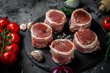 Raw beef filet Mignon steak on metel tray with pepper and salt, filet mignon. beef tenderloin steaks wrapped in bacon and thyme on dark background. top view