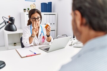 Middle age man and woman wearing doctor uniform prescribe pills at clinic