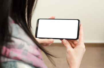 Female hands hold a smartphone mockup. Phone with a blank white display in female hands.