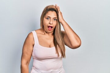 Fototapeta premium Middle age hispanic woman wearing casual style with sleeveless shirt surprised with hand on head for mistake, remember error. forgot, bad memory concept.