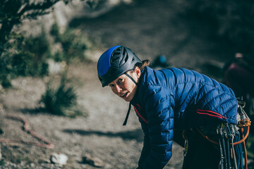 Climber woman with blue helmet and jacket during a rest between climb journey