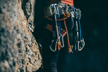 Detail of climb gear and equipment attached to a woman climbing harness while she climbs a route - 487085992