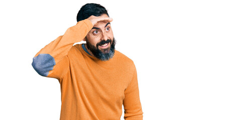Hispanic man with beard wearing casual winter sweater very happy and smiling looking far away with...
