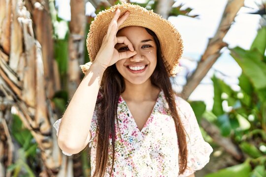 Young brunette woman outdoors on a sunny day of summer pointing thumb up to the side smiling happy with open mouth
