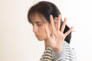 Hand gesture Stop, No. Woman rises her hand up, covering her face and showes stop gesture by hand trying to stop any coming danger. Nonverbal language sign
