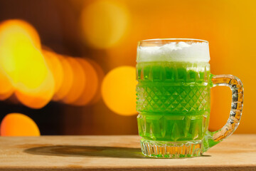 St Patrick day background, copy space. Glass of green beer on festive background with golden bokeh...