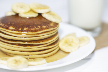 Pancakes with maple syrup and bananas.