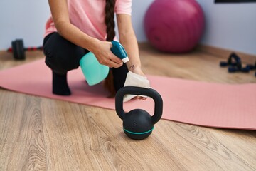 Young hispanic woman cleaning kettlebell at sport center
