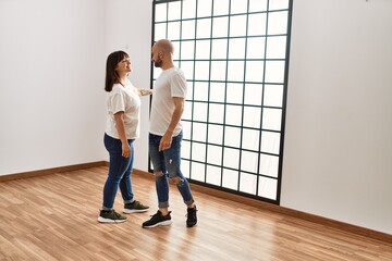 Young hispanic couple smiling happy dancing at empty new home.