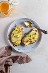 A sandwich with caramel pears, nuts, and honey on a gray plate. 