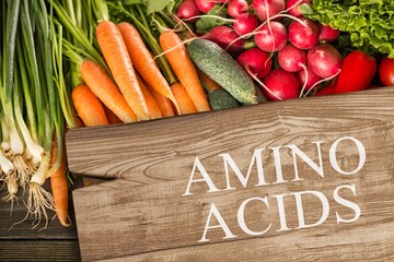 Wooden board with text AMINO ACIDS among different products and vegetables