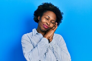 Fototapeta na wymiar Young african american woman wearing casual clothes sleeping tired dreaming and posing with hands together while smiling with closed eyes.