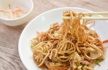 fried yakisoba Japanese noodles slice pork and cabbage with carrot topping dry fish on plate