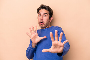 Young caucasian man isolated on beige background being shocked due to an imminent danger