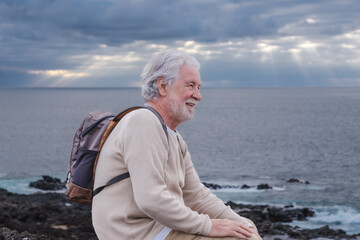 Fototapeta na wymiar Adult old senior bearded man resting during excursion at sea looking at horizon over water. Caucasian elderly white-haired male enjoying free time, vacation and nature in seascape. Copy space