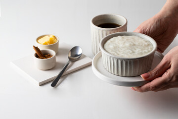 Hand holding ceramic bowl with rice porridge on Risengrod for breakfast.