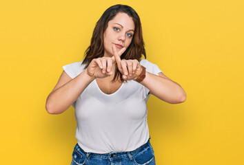 Young plus size woman wearing casual white t shirt rejection expression crossing fingers doing negative sign - obrazy, fototapety, plakaty