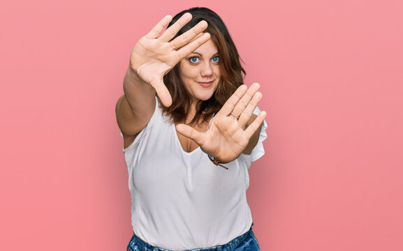 Young plus size woman wearing casual white t shirt doing frame using hands palms and fingers, camera perspective