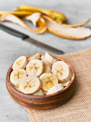Photo of banana slices in a bowl on a concrete surface