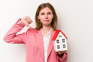 Young business English woman holding house toy isolated on white background showing a dislike...