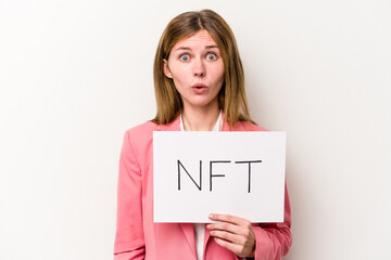 Young English woman holding a NFT placard isolated on white background shrugs shoulders and open eyes confused.