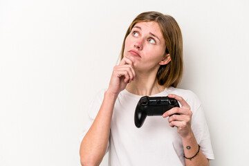 Young English woman playing with a video game controller isolated white background looking sideways with doubtful and skeptical expression.