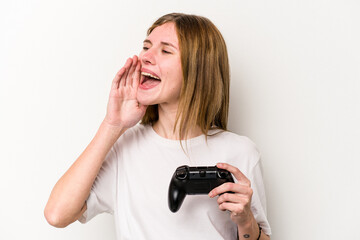 Young English woman playing with a video game controller isolated white background shouting and holding palm near opened mouth.