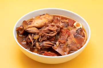 fresh tasty squid stew in white bowl on yellow