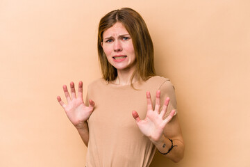 Young English woman isolated on beige background rejecting someone showing a gesture of disgust.
