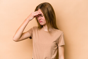 Young English woman isolated on beige background having a head ache, touching front of the face.