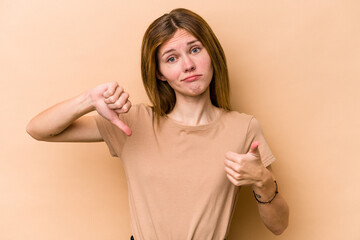 Young English woman isolated on beige background showing thumbs up and thumbs down, difficult...