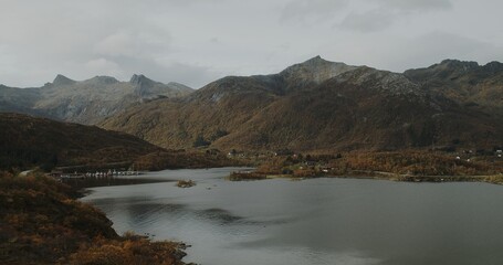 A sea inlet in the Lofoten islands with a marina and mountains in the distance. 