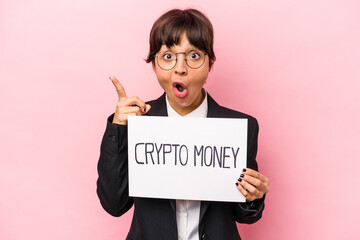Young hispanic business woman holding a crypto money placard isolated on pink background having an idea, inspiration concept.