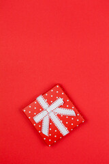 Red gift box with a bow on a red background. Valentine's Day.