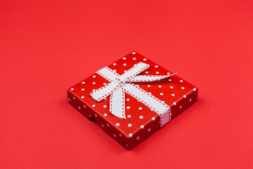 Red gift box with a bow on a red background. Valentine's Day.