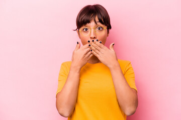 Young hispanic woman isolated on pink background shocked covering mouth with hands.