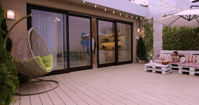 man opens sliding doors, going out on rooftop patio with cozy lounge zone