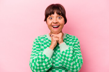 Young hispanic woman isolated on pink background praying for luck, amazed and opening mouth looking to front.