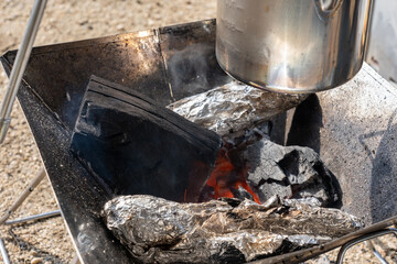 焚火台の上で温めるケトルと墨