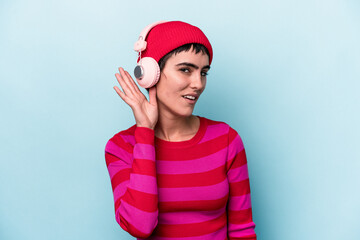 Young caucasian woman listening to music isolated on background trying to listening a gossip.