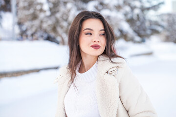 Portrait of a young beautiful brunette woman in winter park