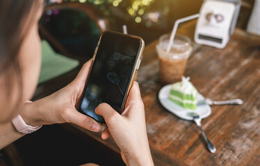 Close-up of a woman's hand holding a modern smartphone enjoying food photography.  Technology concept