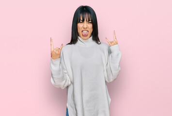 Young brunette woman with bangs wearing casual turtleneck sweater shouting with crazy expression...