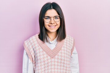 Fototapeta premium Young brunette woman wearing elegant sweater and glasses looking positive and happy standing and smiling with a confident smile showing teeth